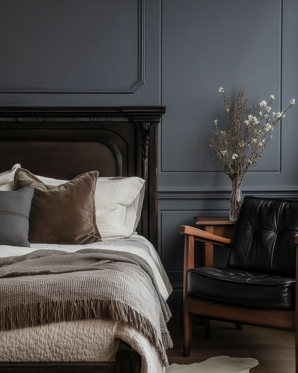 A navy panelled bedroom with linen bedding and a dark wood headboard